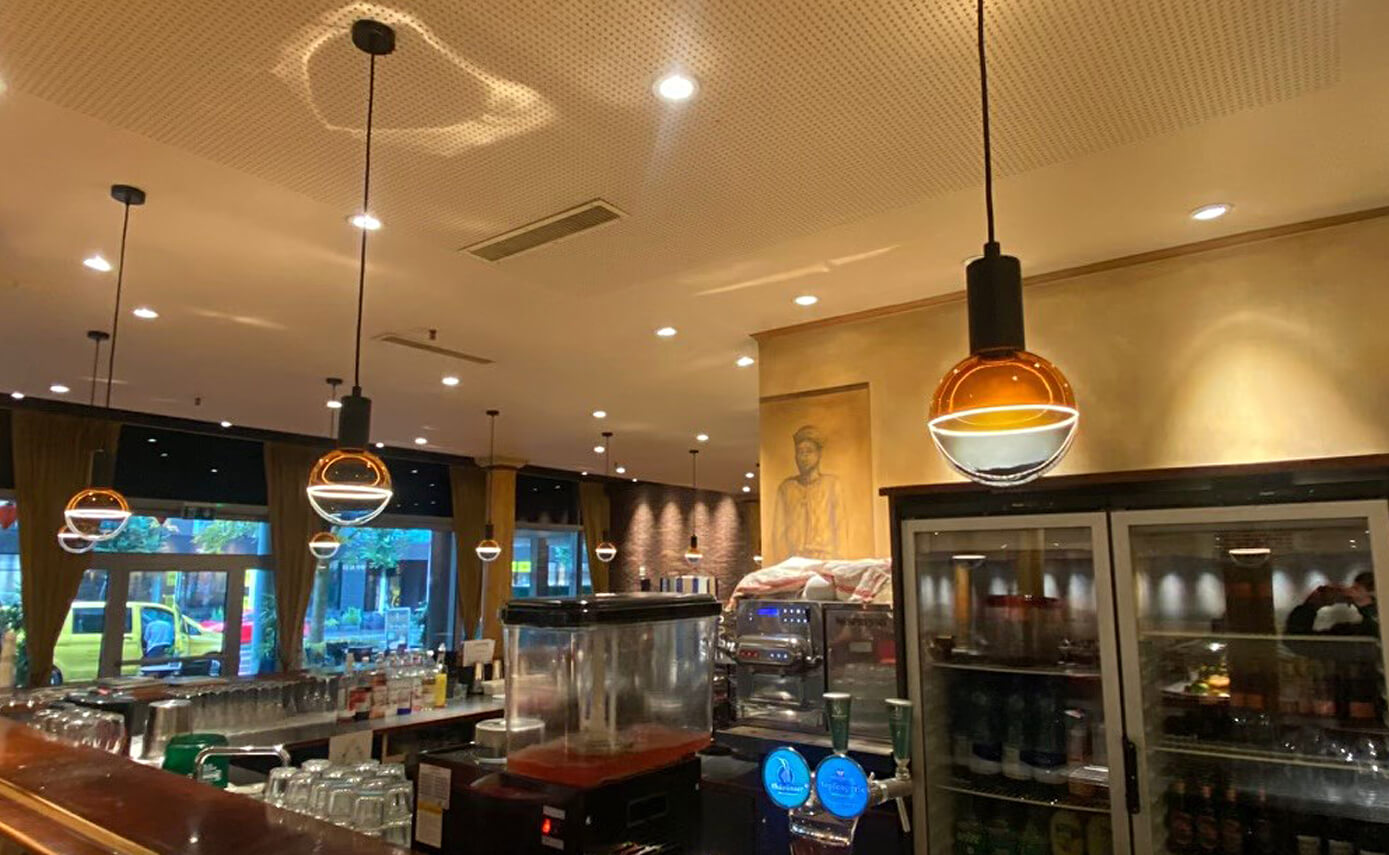 Reference image of Restaurant Han in Zug, showing blue and yellow light bulbs suspended above a bar