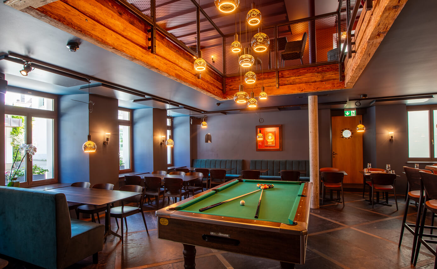 Reference image of the Goldener Anker restaurant in Interlaken, pool table with a gallery and numerous floating light fittings