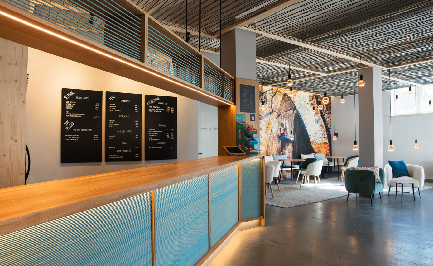Reference image of the Rainbow Rocket bouldering hall in Burgberg, reception desk and floating lights in the lounge area